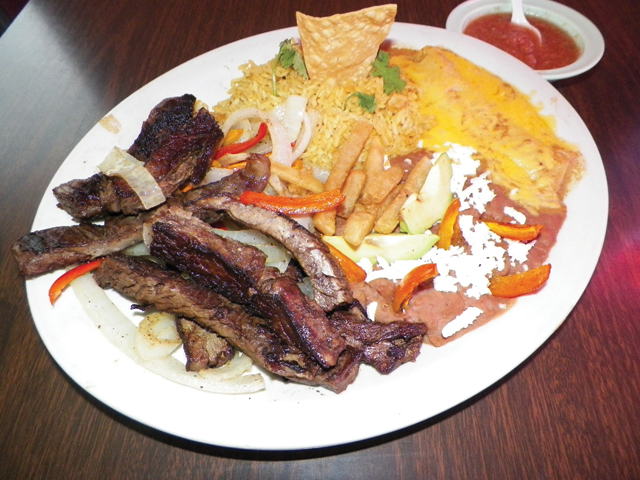 Dishes displaying a botana (for one), with fajitas, enchiladas, Spanish rice, refried beans topped with queso, grilled onions and french friends; chips, salsa, and a torta stuffed with meat, veggies and beans are seen here at Pilo’s Mexican Café. (Staff photos by Heather Cathleen Cox)
