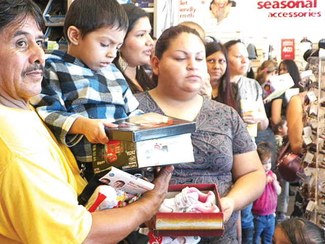 Parents and students of the San Benito Head Start are seen at the local Payless Shoe Source, where Santa Claus distributed sneakers and other assorted foot apparel to the children. Shown with Santa during the giveaway are 3-year-old Leonardo Miranda and 4-year-old Victoria Heredia. (Staff photos by Heather Cathleen Cox)
