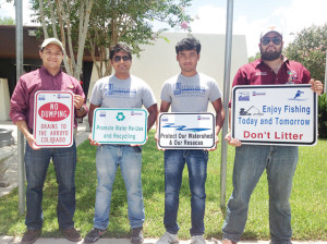 San Benito News photo by Michael Rodriguez Seen, from l-r, displaying no dumping signs at the San Benito Public Library Tuesday are Texas A&M University-Kingsville research engineer Augusto Sanchez and TAMUK graduate students Shrey Kankaria and Nithesh Kattekola. Also shown, far right, is City of San Benito storm water officer Jose Figueroa.