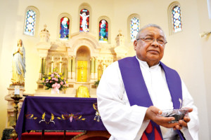 (Staff photo by Francisco E. Jimenez) Father Ignacio “Nacho” Luna is shown at the altar of St. Benedict’s Catholic Church holding ashes, which will be distributed at Catholic churches around the world in observance of Ash Wednesday.