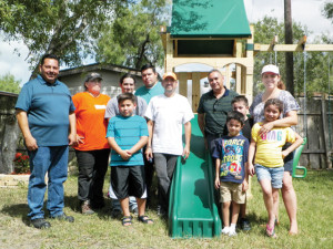 (Staff photo by Heather Cathleen Cox) The family of Sylvia Munoz Rosas are seen at their San Benito home on Wednesday with representatives of Home Depot in as well as local community members after the Harlingen business donated a playground to the family.